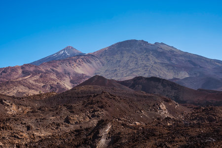 Winter view on colorful volcano Pico del Teide with snow spots from hiking trail Samara. Mountains and lava fields against blue sky. El Teide National Park, Tenerife, Canary Islands, Spainの写真素材