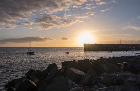 Golden sunset view of Playa de San Juan bay with protected sand beach and small harbor. Playa de San Juan is a small fishing village on the south west of Tenerife island.の写真素材