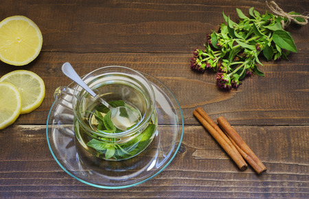 mint tea in a glass transparent cup on a saucer with lemon and cinnamonの写真素材