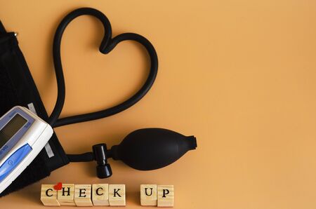 The word chesk up and a device for measuring blood pressure on an orange background 3