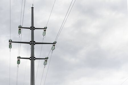 Pillar and power lines against a cloudy skyの写真素材
