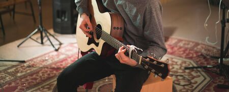 Young man playing on acoustic guitar