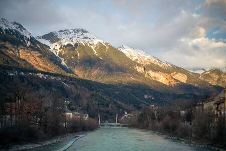 Alpine mountains with snowy peaks. Old european houses. Blue sky with clouds.