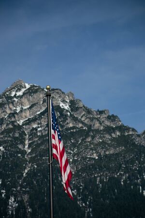Wawing american flag against mountains of rocks and blue skyの写真素材