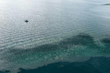Man in an inflatable boat with a fishing rod in the sea