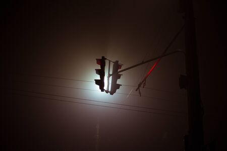 Traffic light at night in the city in the fog