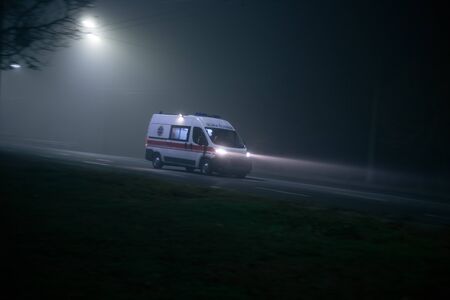 Ambulance rushes in the fog at nightの写真素材
