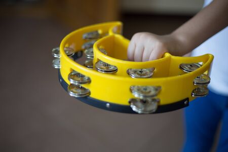 Children's hand holds a yellow tambourine.の写真素材
