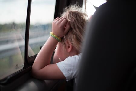 Little girl looks out the side window of the car