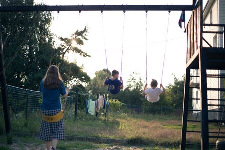Kids in the backyard swing at sunsetの写真素材