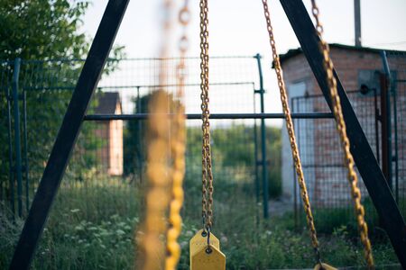 Yellow rubber swing on chains in the backyardの写真素材