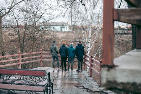 Four guys stand on the bridge near the riverの写真素材