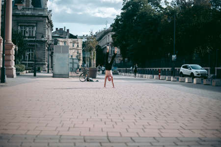 An old bald man with a naked torso handstands in the city centerのeditorial素材