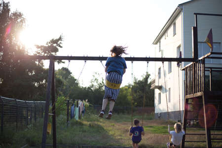 Kids in the backyard swing at sunsetのeditorial素材