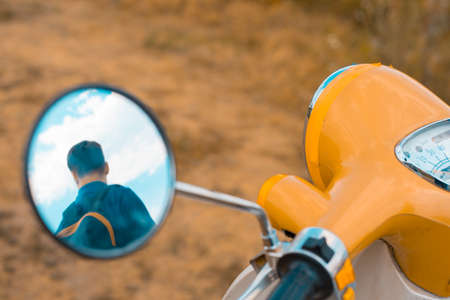 Reflection of a man in the side mirror of a motorbikeのeditorial素材