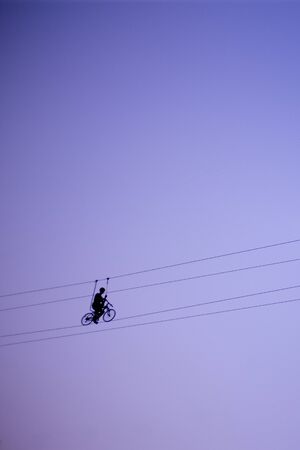 Man balancing on a rope against the sky