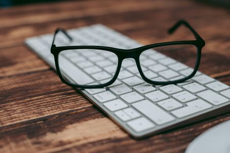 Glasses for sight and vision correction and protection from computer on the wooden table on the keyboardの写真素材