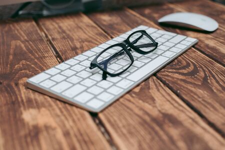 Glasses for sight and vision correction and protection from computer on the wooden table on the keyboardの写真素材