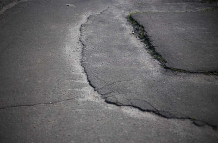 Broken asphalt and cracks on the road surface