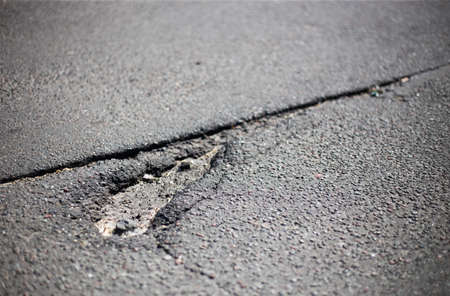 Broken asphalt and cracks on the road surfaceの写真素材