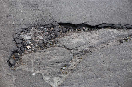 Broken asphalt and cracks on the road surfaceの写真素材