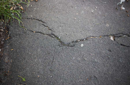 Broken asphalt and cracks on the road surface