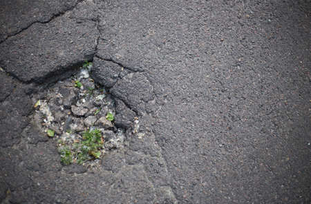 Broken asphalt and cracks on the road surface