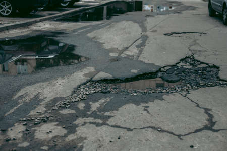 Broken asphalt and cracks on the road surface