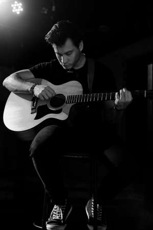 Young handsome guy emotionally sings and speaks into the microphone. Black and white photography