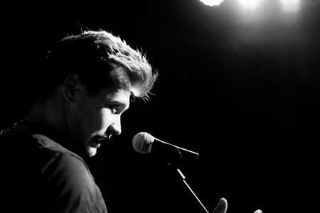 Male hand raised up with bracelets in his hands holds a microphone. Back and white photographyの写真素材
