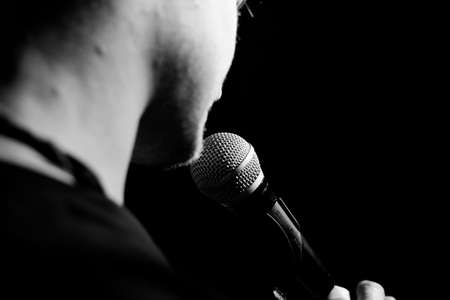 Young handsome guy emotionally sings and speaks into the microphone