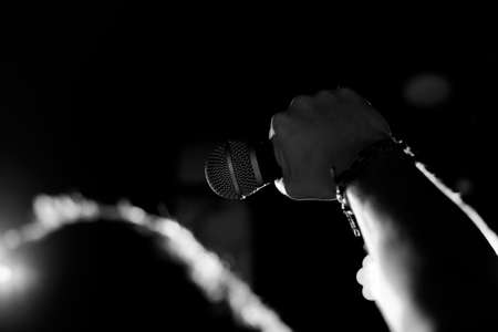 Young handsome guy emotionally sings and speaks into the microphoneの写真素材