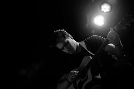 Young handsome guy emotionally sings and speaks into the microphoneの写真素材