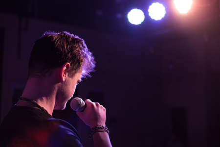 Young handsome guy emotionally sings and speaks into the microphone