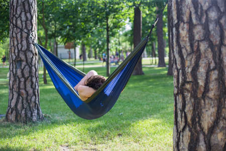Young guy has a rest in summer in a hammock