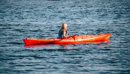 Woman paddling a red kayak in the river in daytimeの写真素材