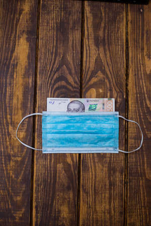 Ukrainian national currency banknote hryvnia and protective medical mask. Cash of the National Bank of Ukraine.の写真素材