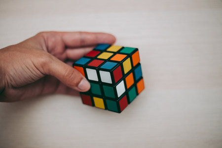 Colored 3D combination puzzle Rubik's cube three by three lies on a wooden tableのeditorial素材