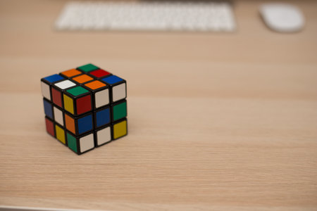 Colored 3D combination puzzle Rubik's cube three by three lies on a wooden tableのeditorial素材
