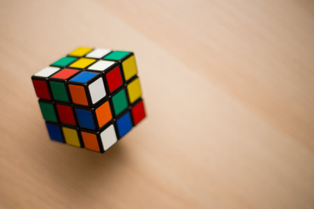 Colored 3D combination puzzle Rubik's cube three by three lies on a wooden tableのeditorial素材
