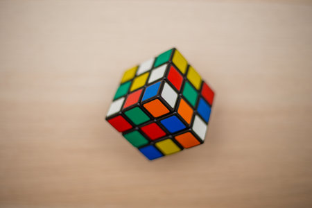Colored 3D combination puzzle Rubik's cube three by three lies on a wooden tableのeditorial素材