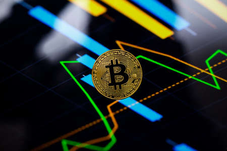 Gold bitcoin coin against the background of the cryptocurrency rate index chart