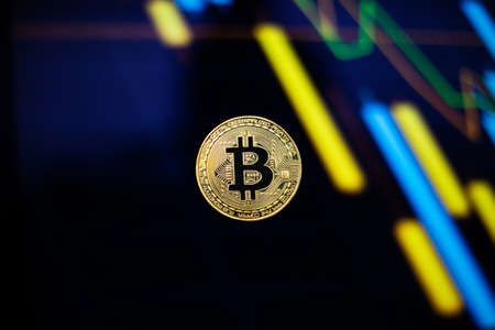 Gold bitcoin coin against the background of the cryptocurrency rate index chart