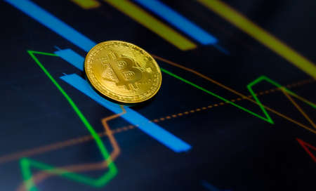 Gold bitcoin coin against the background of the cryptocurrency rate index chart