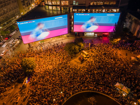 Kyiv, Ukraine 06/30/2020: A large group of fans in the square near large screens with the broadcast of the football match for Euro 2020 between Ukraine and Sweden near Guliver mallのeditorial素材