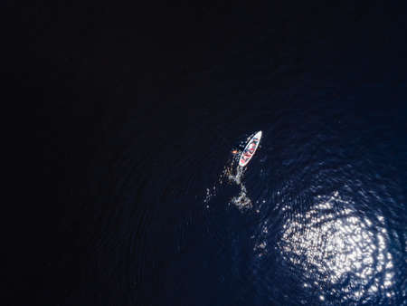 Aerial view from a drone of a person who floats on a sup in the water