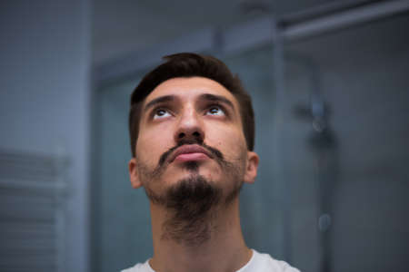 Portrait of a man with a bad heterogeneous beard in the bathroomの写真素材