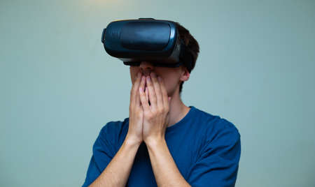 An excited young guy in virtual reality glasses is immersed in the metaverse