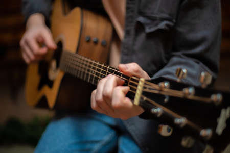 A guy clamps a chord on an acoustic guitar with close-upの写真素材