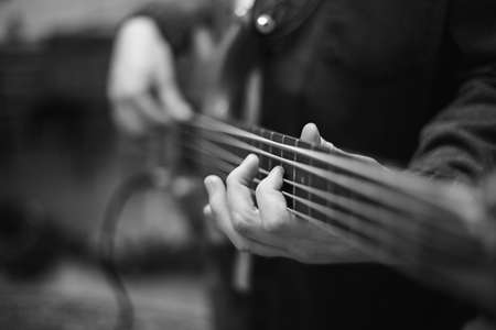 A young guy with a beard plays a bass guitar with five stringsの写真素材